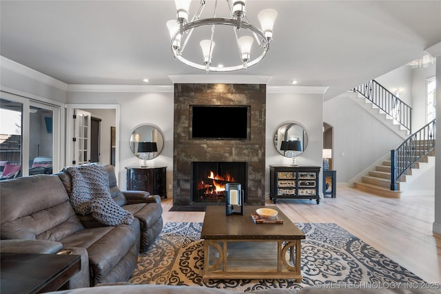 living room featuring a notable chandelier, a fireplace, stairs, and crown molding