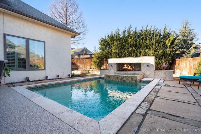 view of pool with a patio, fence, a fenced in pool, and a warm lit fireplace