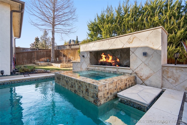 view of swimming pool with a lit fireplace, an in ground hot tub, and fence