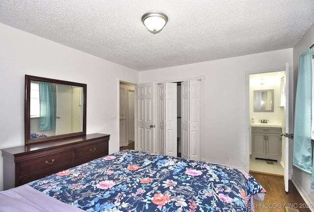 bedroom featuring ensuite bathroom, dark wood-style flooring, a closet, and a textured ceiling