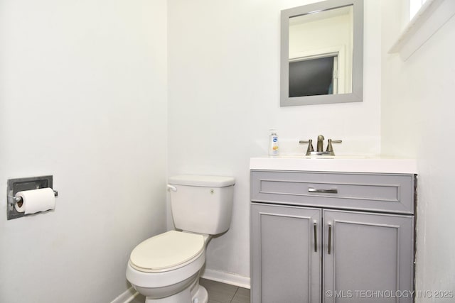 half bath with toilet, vanity, and baseboards