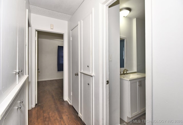 corridor featuring dark wood-type flooring and a sink