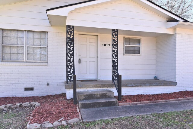 property entrance featuring brick siding and crawl space