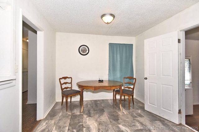 dining area featuring baseboards and a textured ceiling