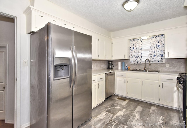 kitchen featuring white cabinets, appliances with stainless steel finishes, light countertops, and a sink