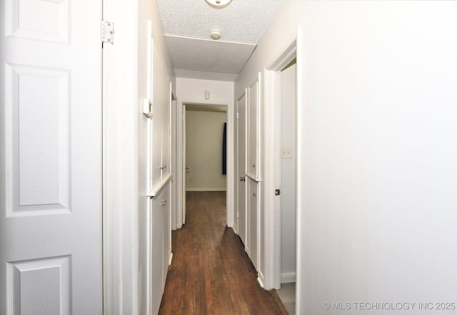 corridor with a textured ceiling and dark wood-style flooring