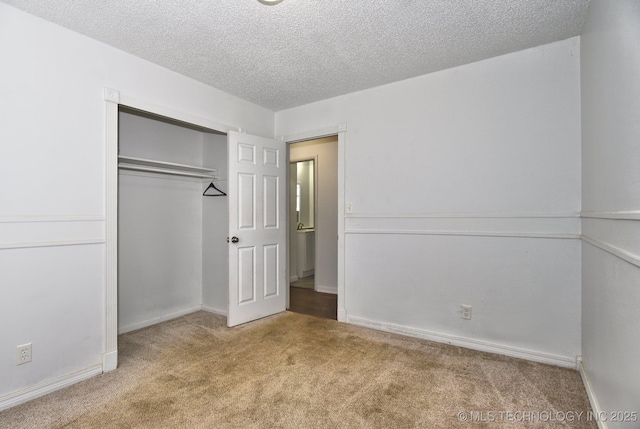 unfurnished bedroom with a closet, baseboards, carpet, and a textured ceiling