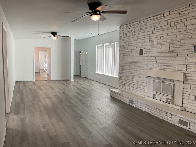 unfurnished living room with ceiling fan, baseboards, wood finished floors, and a fireplace