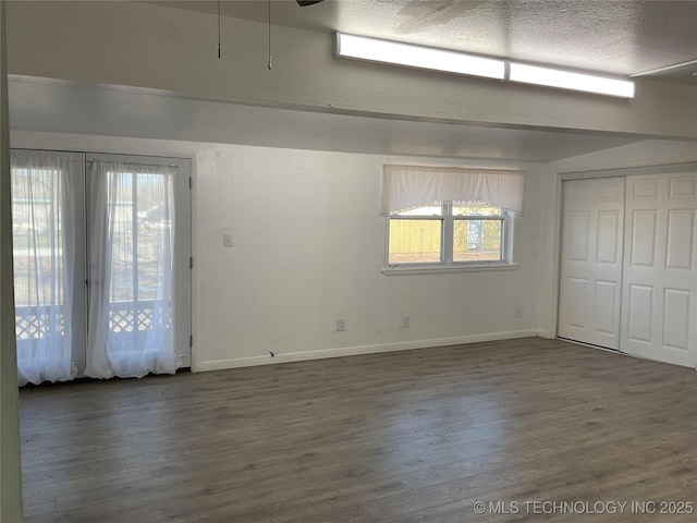 empty room with wood finished floors, baseboards, and a textured ceiling