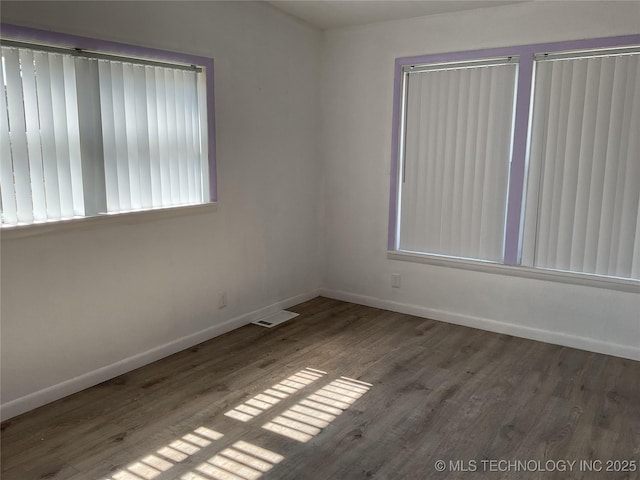 empty room with visible vents, baseboards, and wood finished floors