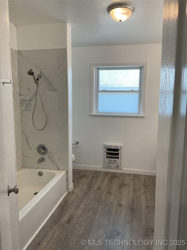 full bath featuring heating unit, shower / bath combination, baseboards, and wood finished floors