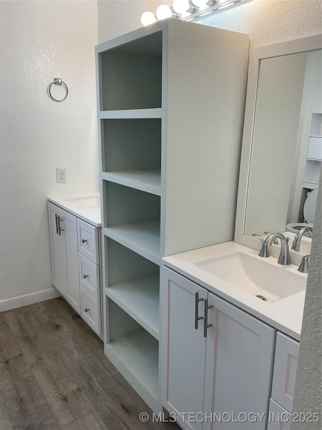 bathroom with vanity, wood finished floors, and baseboards