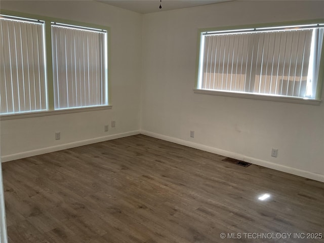 empty room with visible vents, baseboards, and wood finished floors