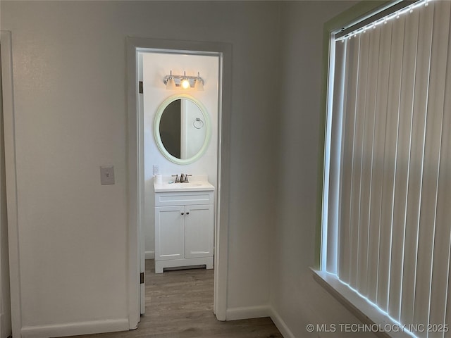 bathroom with baseboards, wood finished floors, and vanity