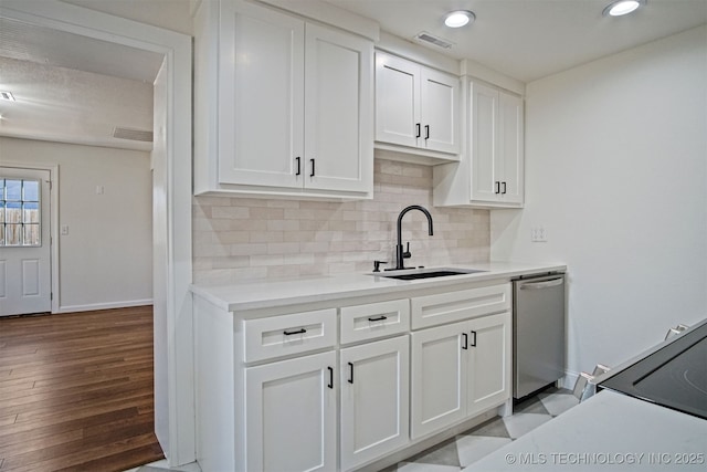 kitchen with visible vents, a sink, stainless steel dishwasher, white cabinetry, and decorative backsplash