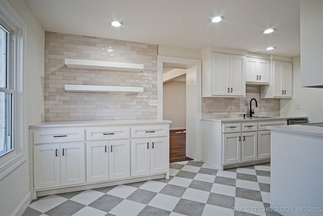 kitchen featuring a healthy amount of sunlight, light floors, light countertops, white cabinets, and a sink