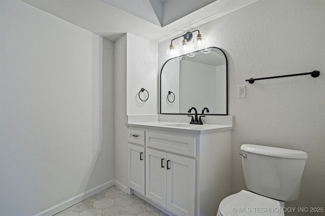 half bathroom featuring vanity, tile patterned floors, toilet, and baseboards