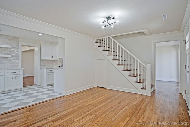 interior space featuring stairs, crown molding, baseboards, and light wood finished floors