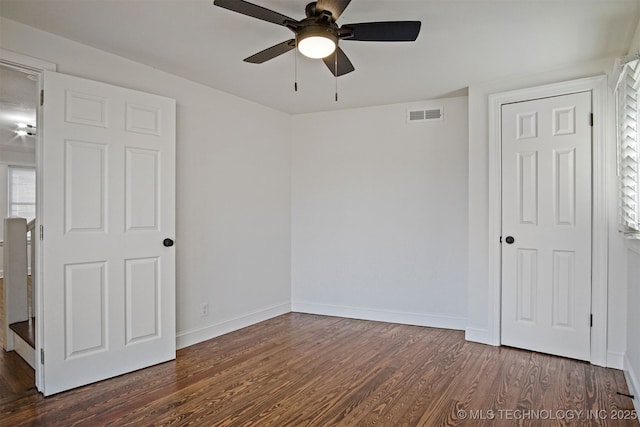 unfurnished bedroom with a ceiling fan, baseboards, visible vents, and dark wood-style flooring