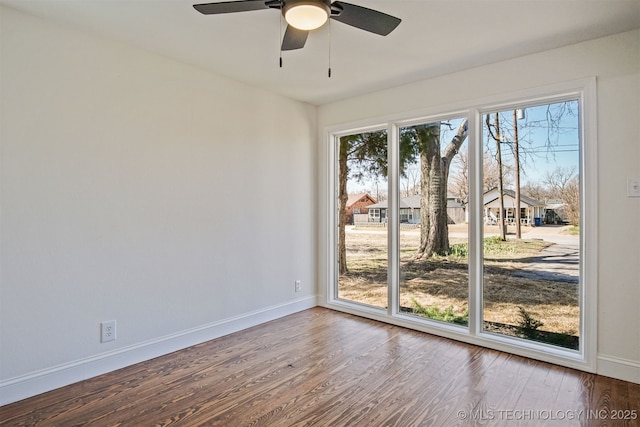 spare room with baseboards, wood finished floors, and a ceiling fan