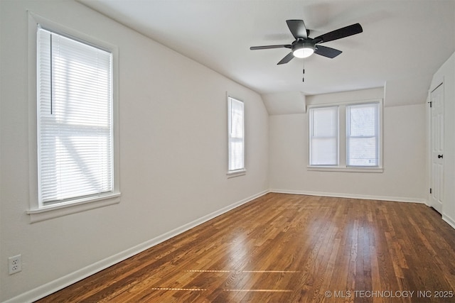 empty room with vaulted ceiling, a ceiling fan, baseboards, and wood-type flooring