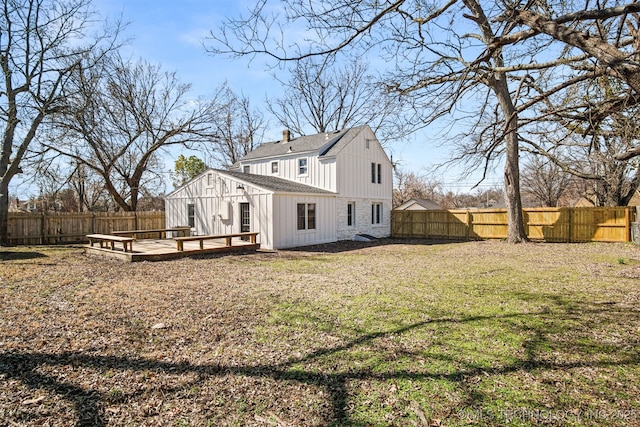 rear view of house with a wooden deck, a fenced backyard, a lawn, and a chimney