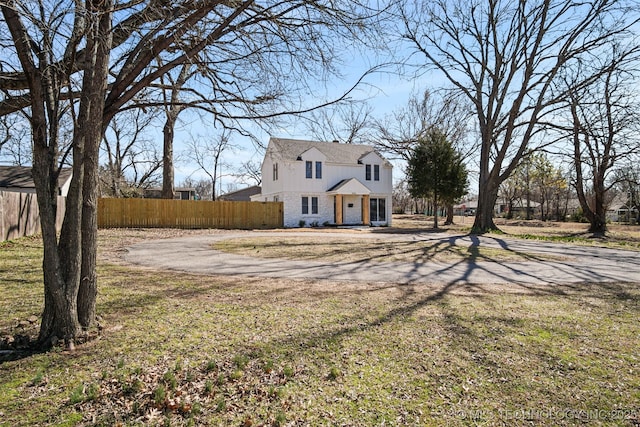 view of front of property with dirt driveway, stone siding, and fence