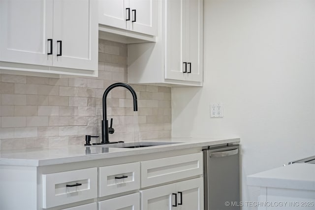 kitchen featuring a sink, backsplash, light countertops, and white cabinetry