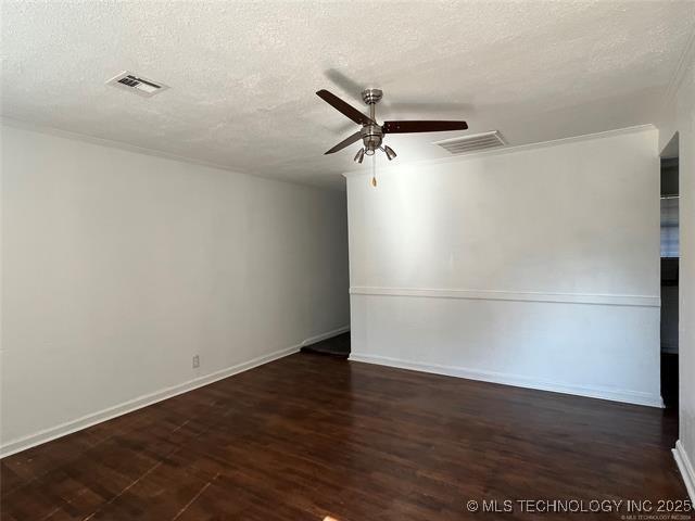 empty room featuring a ceiling fan, wood finished floors, visible vents, and a textured ceiling