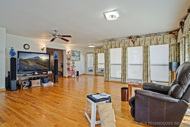 living area featuring ceiling fan, baseboards, and wood finished floors