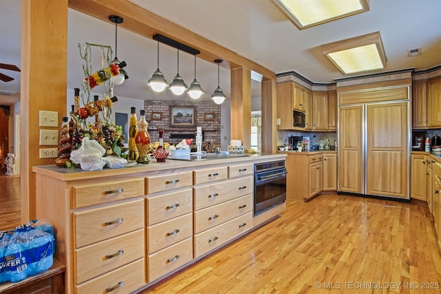 kitchen featuring decorative light fixtures, black appliances, light wood-type flooring, and light countertops