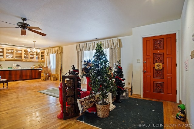 entryway featuring wood finished floors and ceiling fan with notable chandelier