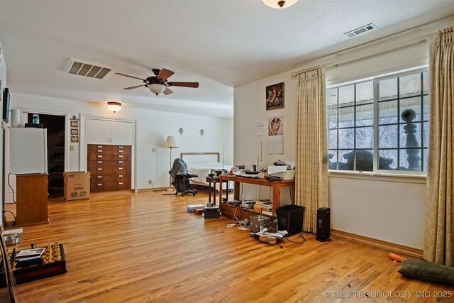 office area with visible vents, ceiling fan, light wood-type flooring, and baseboards