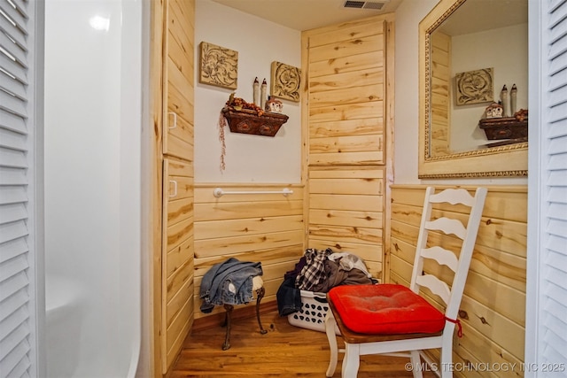 hallway with visible vents, wood walls, and wood finished floors