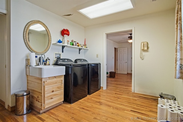 laundry area featuring a ceiling fan, washing machine and clothes dryer, laundry area, light wood-style flooring, and a sink