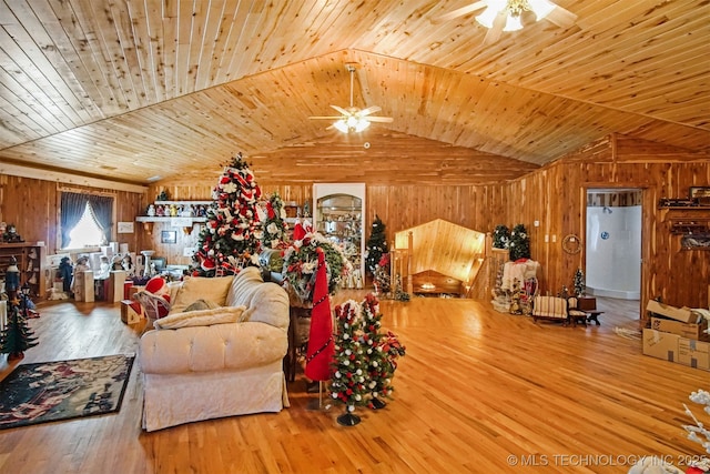 living area with wooden walls, a ceiling fan, and hardwood / wood-style flooring