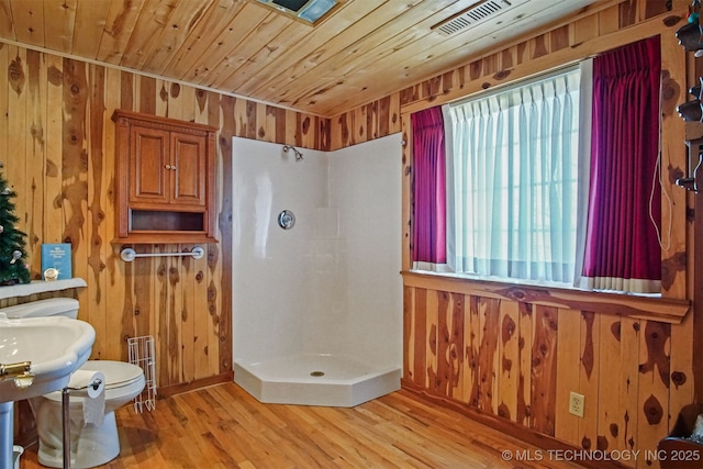 bathroom with wood finished floors, wood ceiling, wood walls, and a shower stall