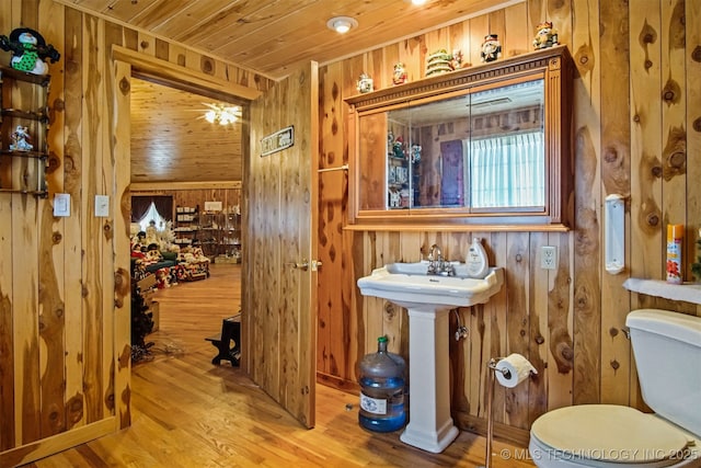 half bath featuring wooden ceiling, toilet, wood finished floors, and wood walls