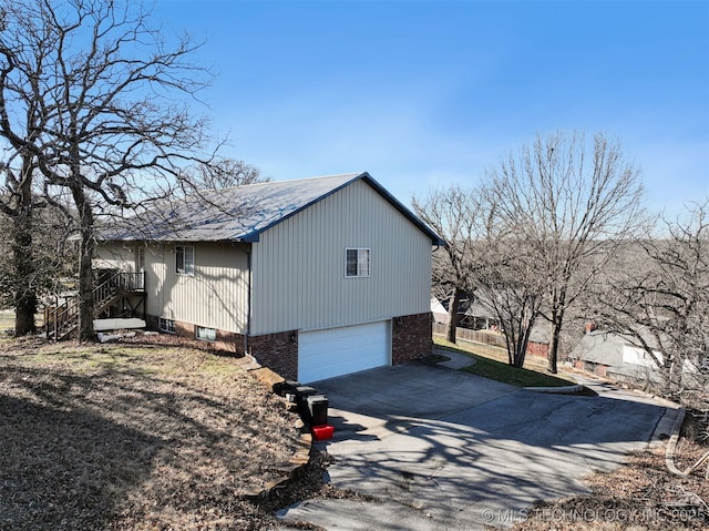 view of home's exterior with brick siding, a garage, and driveway