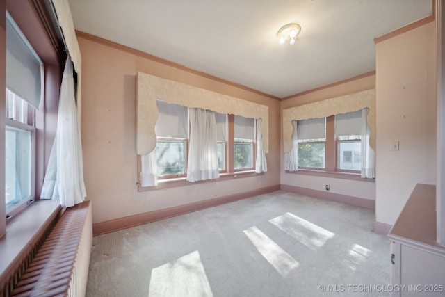 carpeted spare room with baseboards and crown molding