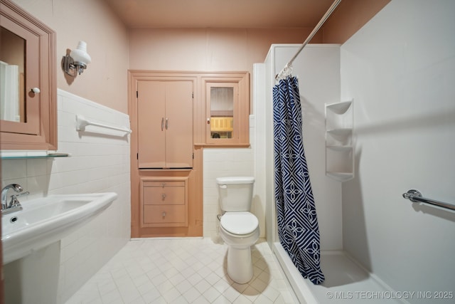 1340 E 9th St, Okmulgee, OK 74447 - bathroom featuring tile walls, tile patterned flooring, toilet, a shower with curtain, and wainscoting