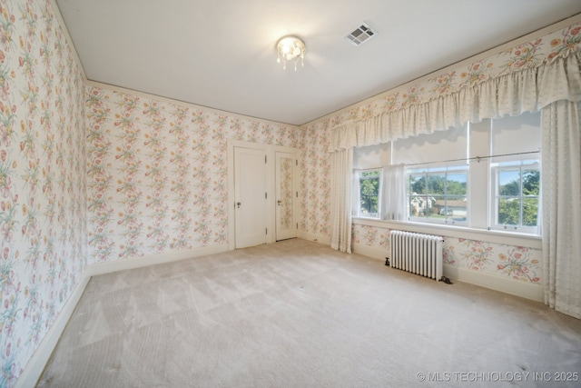 spare room featuring visible vents, light colored carpet, radiator, and wallpapered walls