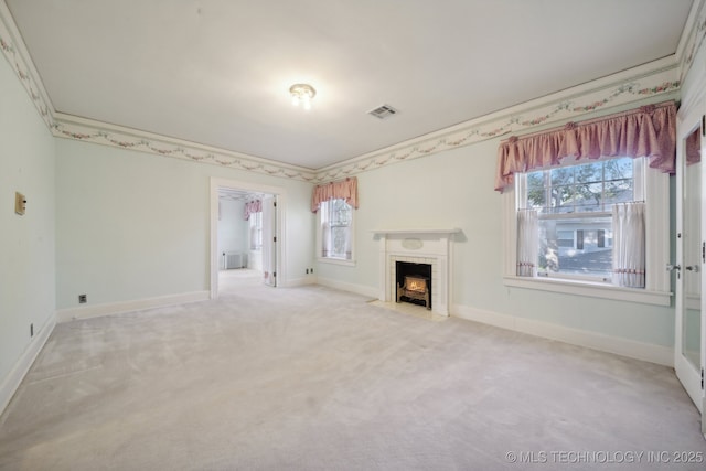 unfurnished living room with plenty of natural light, ornamental molding, carpet flooring, and a tiled fireplace