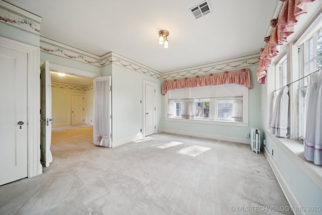 unfurnished bedroom featuring radiator heating unit, baseboards, visible vents, and carpet floors