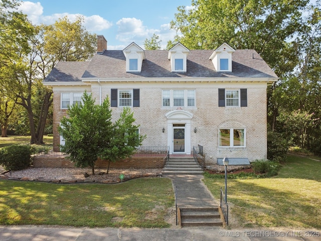 1340 E 9th St, Okmulgee, OK 74447 - colonial home with a front yard, a chimney, and brick siding