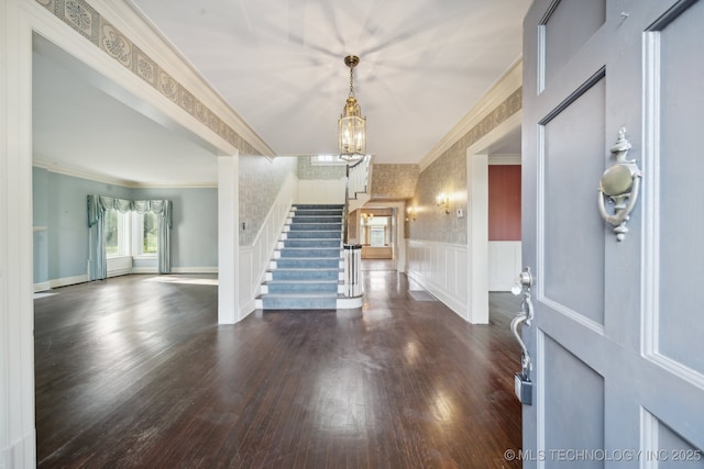 entrance foyer featuring stairway, wainscoting, wood finished floors, and ornamental molding