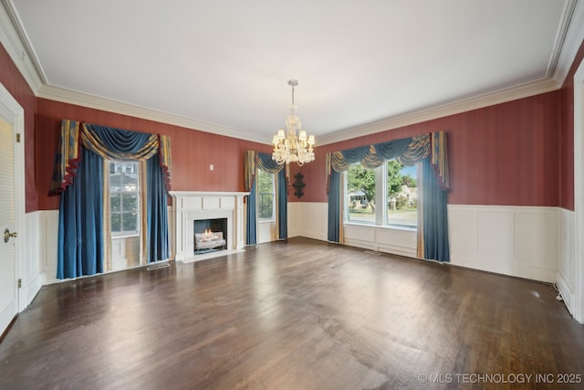 unfurnished living room with a wainscoted wall, a fireplace with flush hearth, wood finished floors, crown molding, and a chandelier