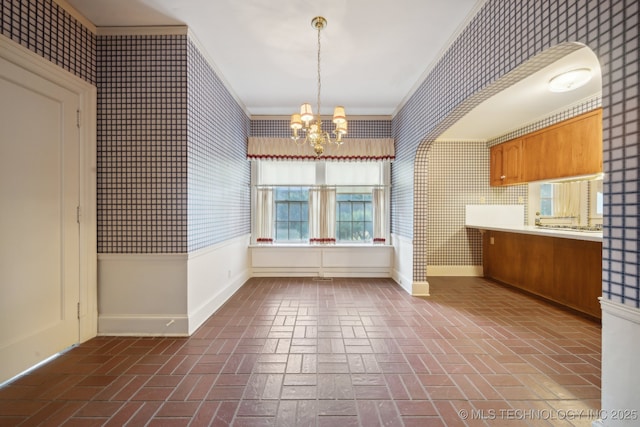 interior space featuring wallpapered walls, baseboards, brick floor, hanging light fixtures, and a notable chandelier