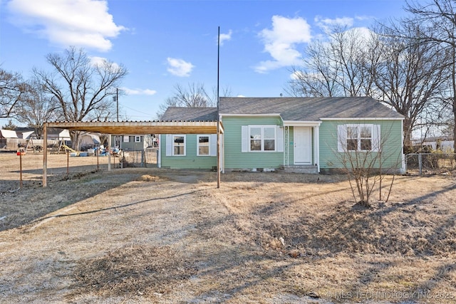 view of front of property featuring dirt driveway, a carport, and fence