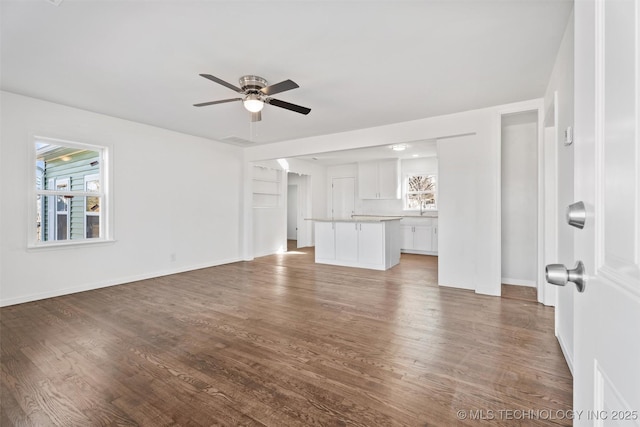 unfurnished living room with baseboards, ceiling fan, and wood finished floors